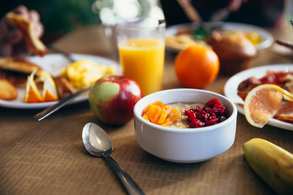 Frukostbord med havregrynsgröt, frukt, apelsinjuice och banan